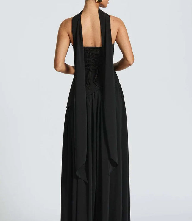 Back view of black halter maxi dress with open back, lace-up detail, and long drape