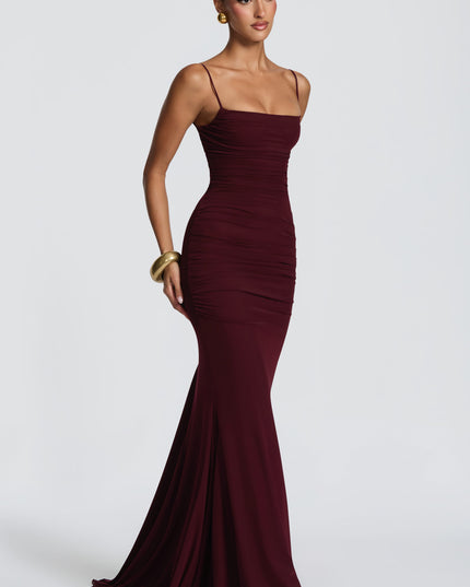 Burgundy ruched maxi dress side view showing fitted waist and hip ruching with floor-length hem