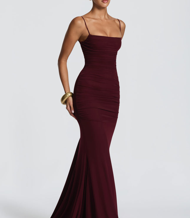 Burgundy ruched maxi dress side view showing fitted waist and hip ruching with floor-length hem