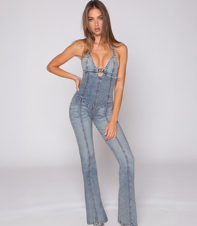 Front view of a fitted light blue denim jumpsuit with halter straps, cutout bust, and flared legs