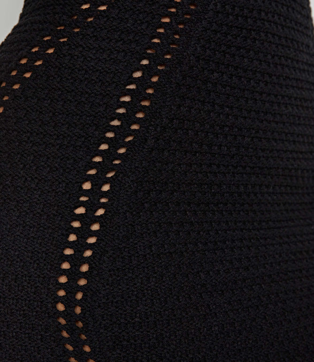 Close-up detail of the black crochet mini dress showing intricate open-knit patterns on the side.