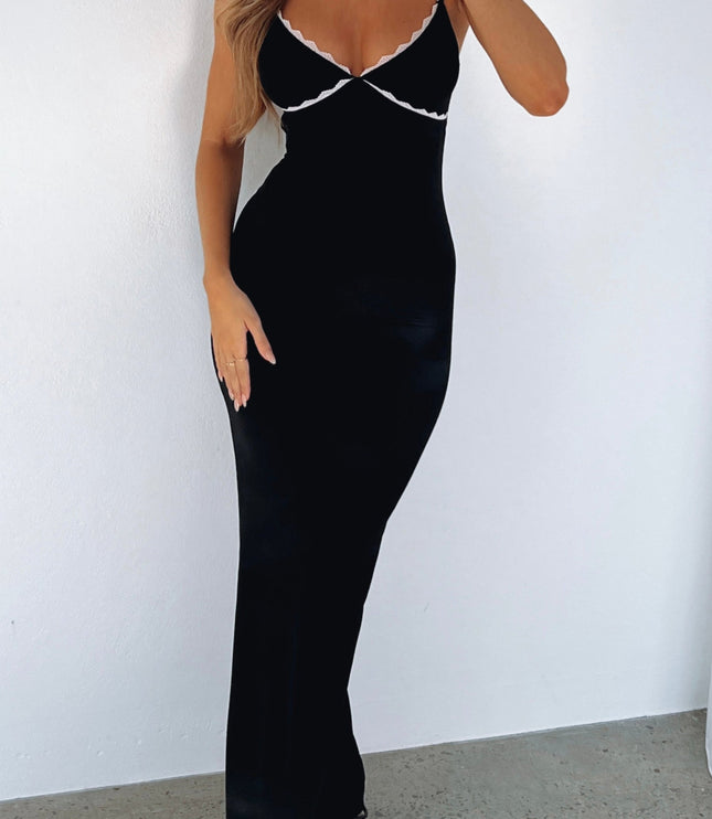 Black lace trim maxi dress with adjustable straps, fitted silhouette, and white lace detail on bust, paired with black heels.