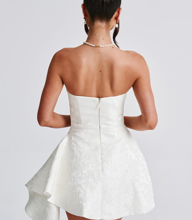 Back view of a white floral strapless mini dress, showing the zipper closure and draped skirt detail.