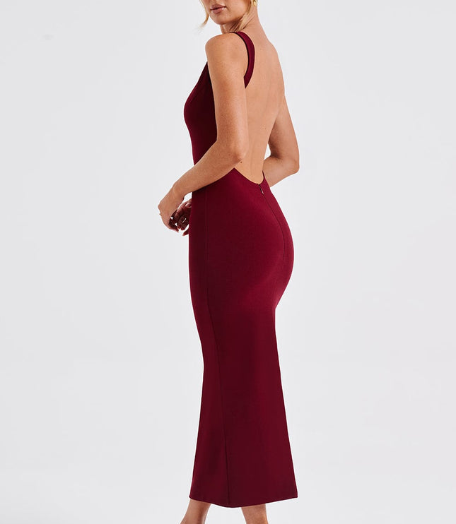 Side profile of a women's burgundy midi dress, emphasizing the low back and tailored fit, paired with nude heels.