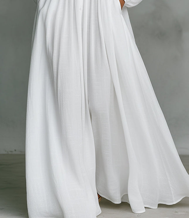 Detail shot of the wide-leg pants on the white button-down jumpsuit, showing flowy fabric and side pockets.