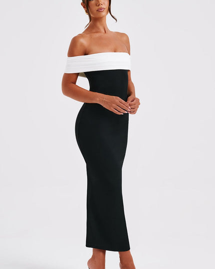 Side profile of women's black and white off-shoulder pleated bardot midi dress, with hands clasped and black heels.