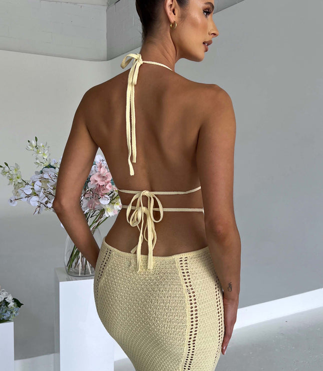 Detailed back view of the light yellow crochet knit maxi dress, highlighting the halter ties and textured skirt.