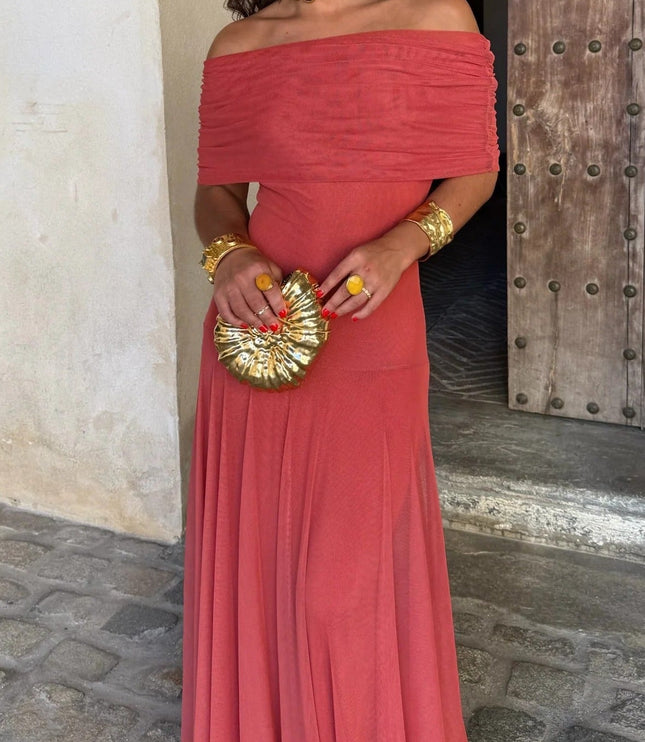 Women's coral red off-the-shoulder drape mesh maxi dress, styled with gold cuffs, rings, and a shell-shaped clutch.