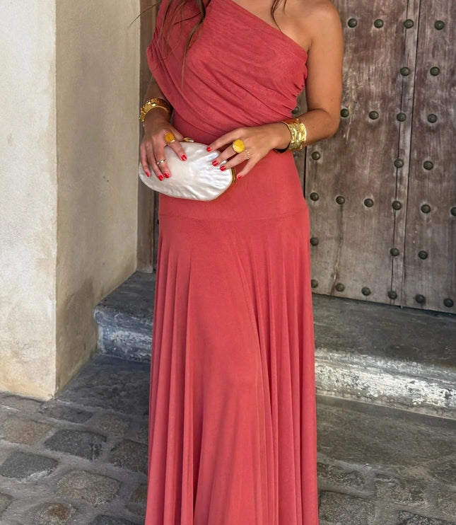 Front view of a women's coral red one shoulder drape mesh maxi dress, paired with a white pearl clutch.