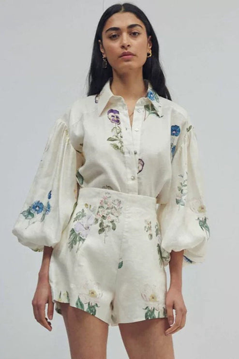 Women's white linen short set with colorful floral print, featuring a button-down balloon sleeve top and high-waisted shorts.