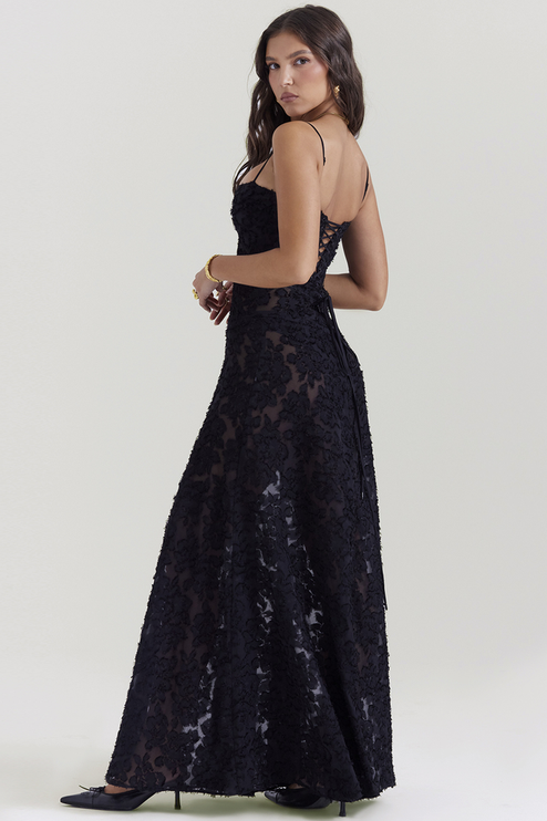 Side view of a black floral maxi dress with a lace-up corset back and thin spaghetti straps, showcasing the intricate floral pattern and full skirt.