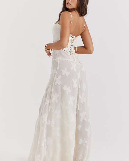 Side view of a white floral corset maxi dress with a lace-up back and delicate butterfly- floral pattern on the full skirt.