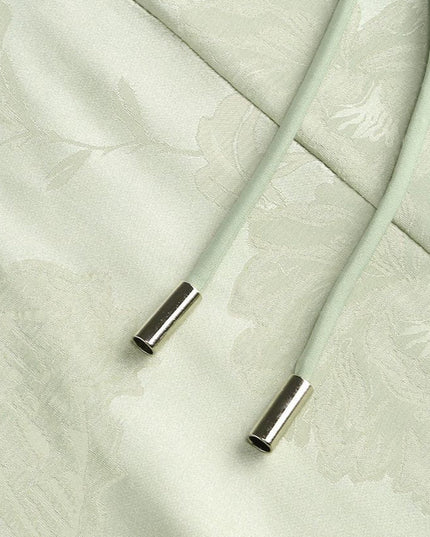 Detail of the light green floral maxi dress showing the ends of the corset laces with silver aglets.