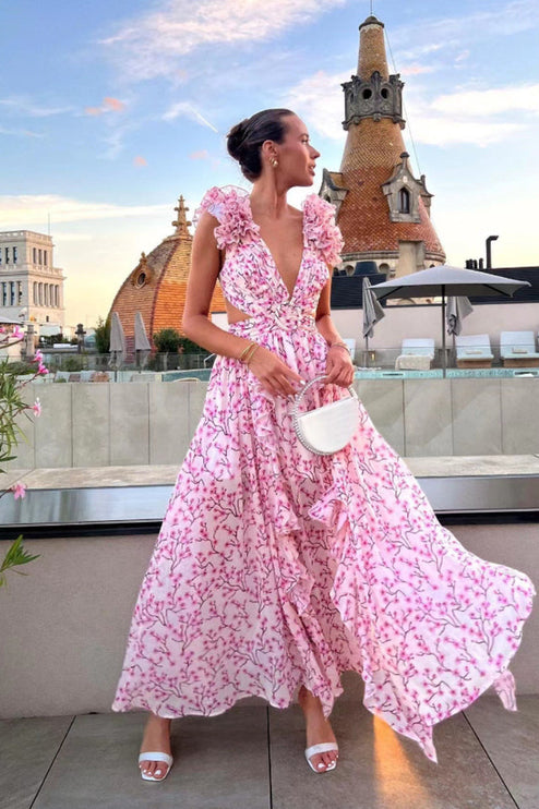 Women's pink floral print maxi dress with deep V-neck, ruffled sleeves, and side cut-outs, worn on a rooftop.