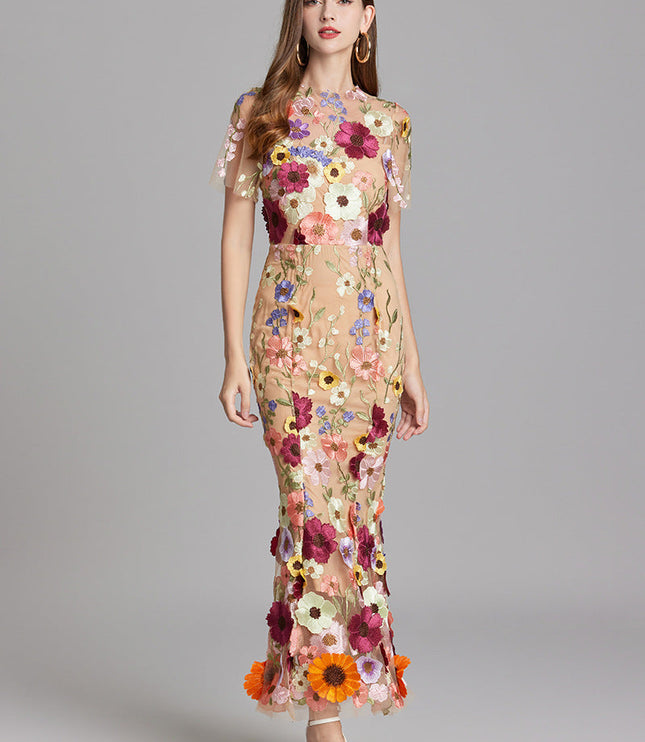 Women's multi-color floral embroidered sheer maxi prom dress, short sleeves, in a confident pose.