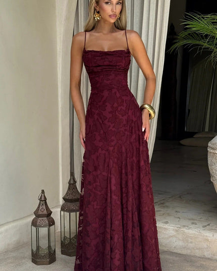 Full-length women's burgundy floral jacquard maxi dress with spaghetti straps, shown in an outdoor setting.