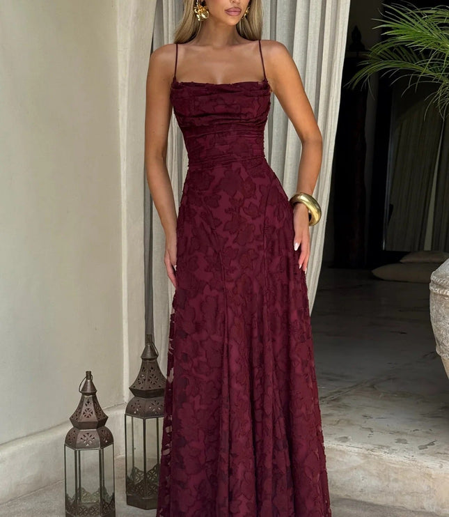 Full-length women's burgundy floral jacquard maxi dress with spaghetti straps, shown in an outdoor setting.