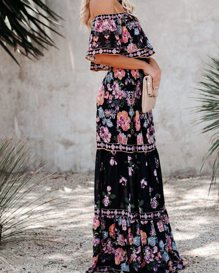 Side view of a women's black floral off-shoulder maxi dress, featuring a tiered skirt and vibrant pink and purple blossoms.