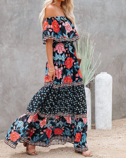 Side profile of a women's black floral off-shoulder maxi dress, showcasing red and blue flowers and a flowing skirt.