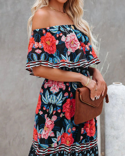 Close-up of the bodice of a women's black floral off-shoulder ruffled maxi dress, with vibrant red and pink blooms.