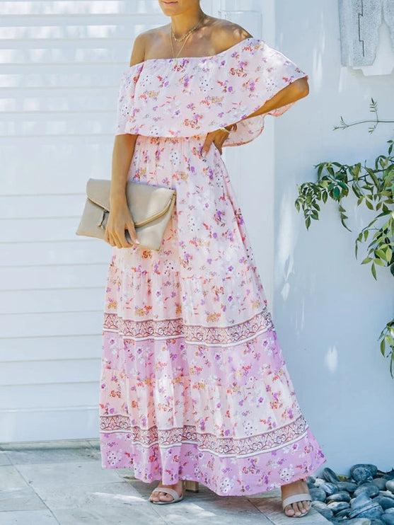 Side view of light pink floral off-shoulder ruffled maxi dress with a tiered skirt and a beige clutch.