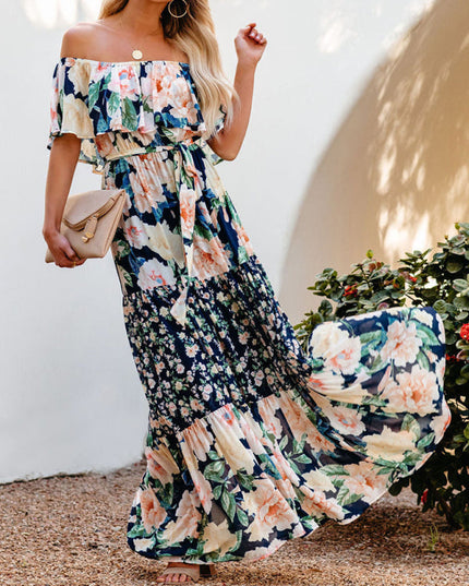 Flowing off-shoulder ruffled floral maxi dress in navy blue, peach, and cream, showing the full tiered skirt in motion.