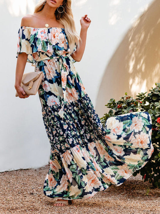Flowing off-shoulder ruffled floral maxi dress in navy blue, peach, and cream, showing the full tiered skirt in motion.