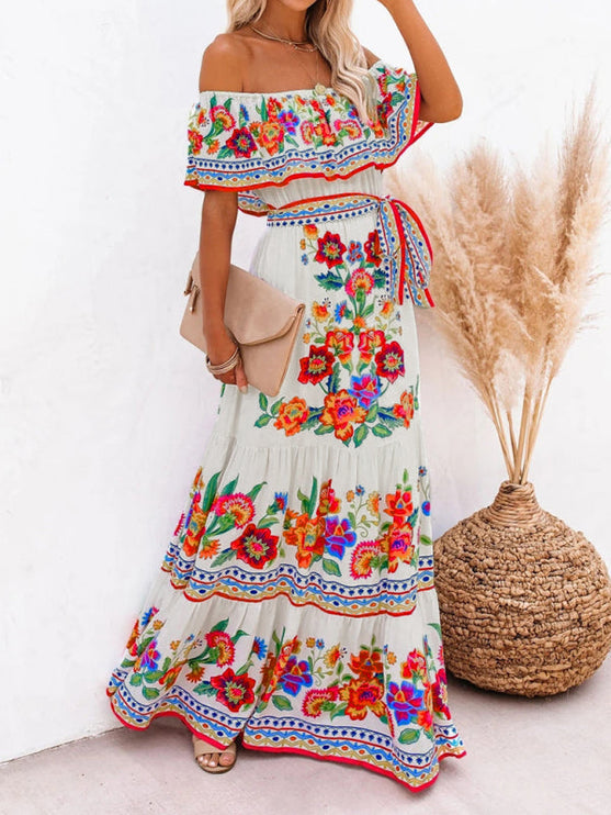 Side profile of a women's white off-shoulder floral maxi dress, showcasing the flowy skirt and colorful design.