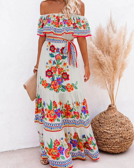 Women's off-shoulder white floral maxi dress with a red and blue patterned border, styled with a clutch.