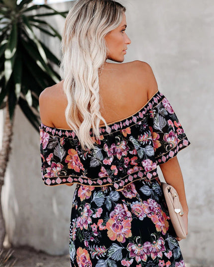 Back view of a women's black off-shoulder maxi dress, highlighting the pink and purple floral pattern and ruffled top.