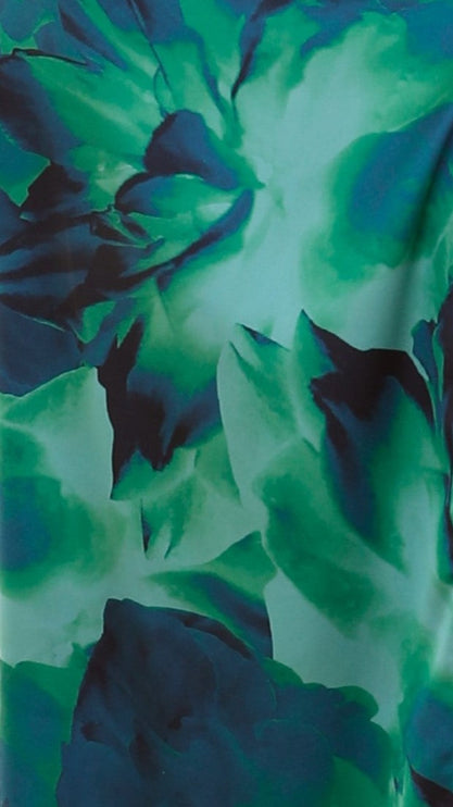 Close-up detail of the vibrant green and blue floral print fabric of the one-shoulder cut-out maxi dress.