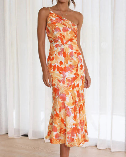 Front view of a woman wearing an orange and white floral one-shoulder ruched bust midi dress, for a wedding.
