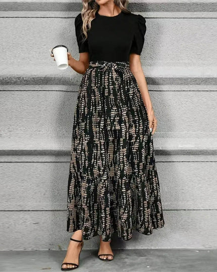 Women's black short sleeve top paired with a high waist maxi dress featuring a dark abstract geometric print in earthy tones.