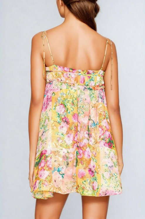 Back view of a women's floral print tie shoulder mini dress, showing the ruffled back and tie details.