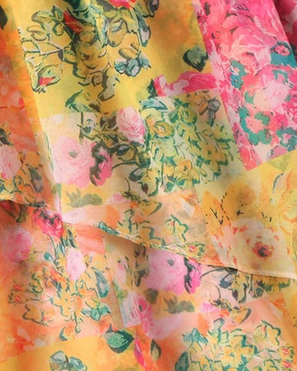 Detailed view of the layered ruffles and vibrant floral print on the tie shoulder mini dress fabric.