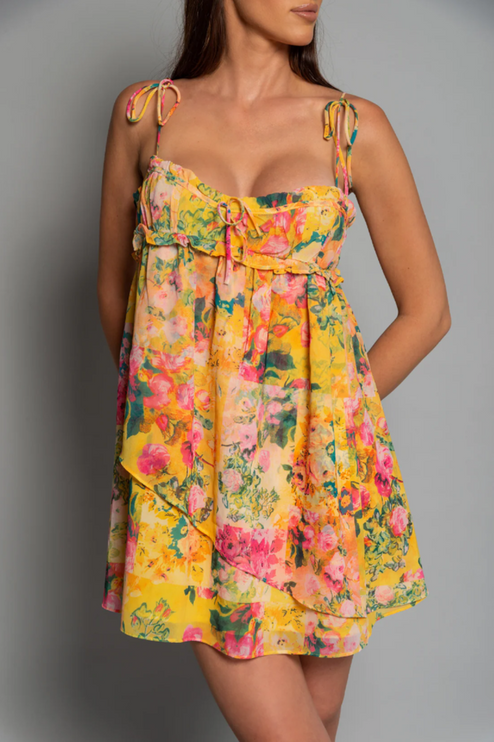 Close-up of the bodice and skirt detail of a women's yellow floral print tie shoulder mini dress.