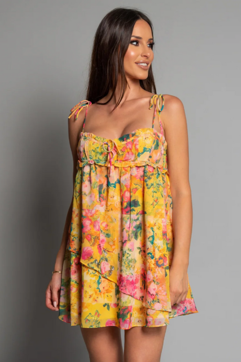 Front view of a women's yellow floral print tie shoulder mini dress with ruffled details.