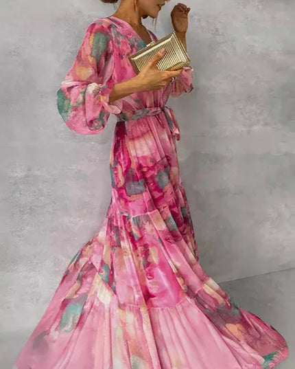 Side profile of a women's flowing pink floral V-neck maxi dress with long bishop sleeves and a cinched waist.