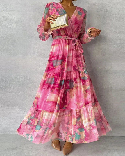Front view of a women's elegant pink floral V-neck long sleeve maxi dress with a full, tiered skirt and tie waist.
