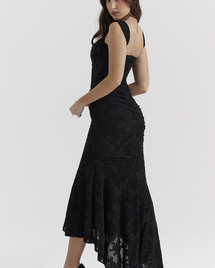 Side profile of a black floral ruched off-shoulder maxi dress, featuring a high-low hem and fitted silhouette with delicate floral texture.