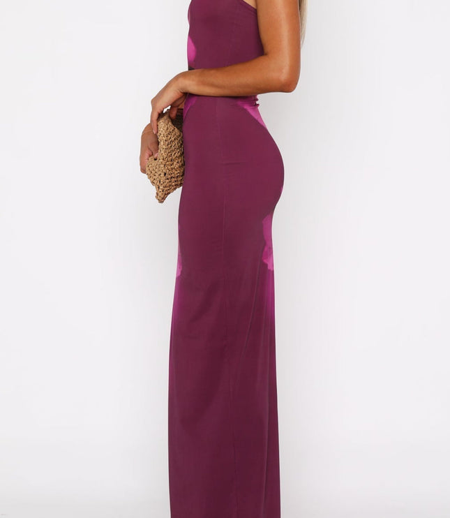 Side profile of a women's magenta floral maxi dress with spaghetti straps and a scoop neckline, holding a woven clutch.