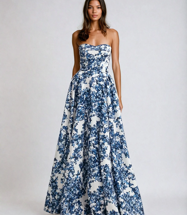 Full body shot of a women's strapless formal maxi dress, adorned with a large blue floral print on a white background.