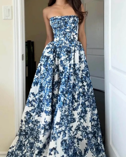 Women's blue floral strapless formal maxi dress with a full skirt, captured in an indoor setting, showcasing its elegant drape.