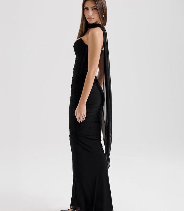 Side view of black strapless ruched maxi dress, showcasing the draped sheer fabric panel.
