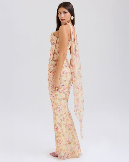 Back three-quarter view of the floral strapless ruched maxi dress, with a flowing sheer panel extending from the back.