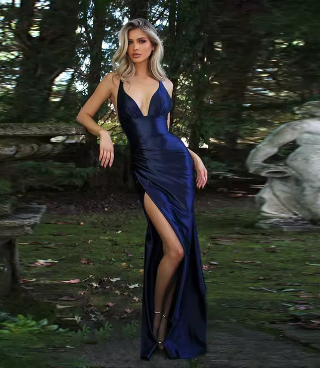 Navy blue formal backless V-neck maxi dress with a high slit, satin- fabric, in a garden setting.