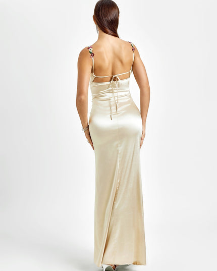 Back view of a champagne formal maxi dress, showcasing the open back with delicate tie details and floral straps.