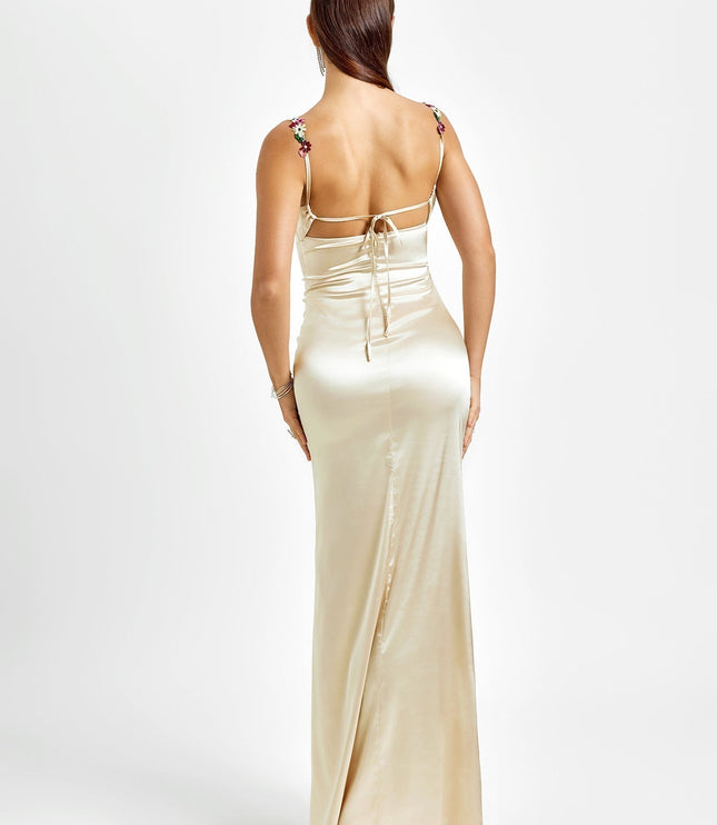 Back view of a champagne formal maxi dress, showcasing the open back with delicate tie details and floral straps.