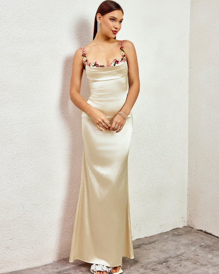 Side profile of a champagne formal maxi dress, highlighting the smooth satin fabric and delicate floral embellishments.