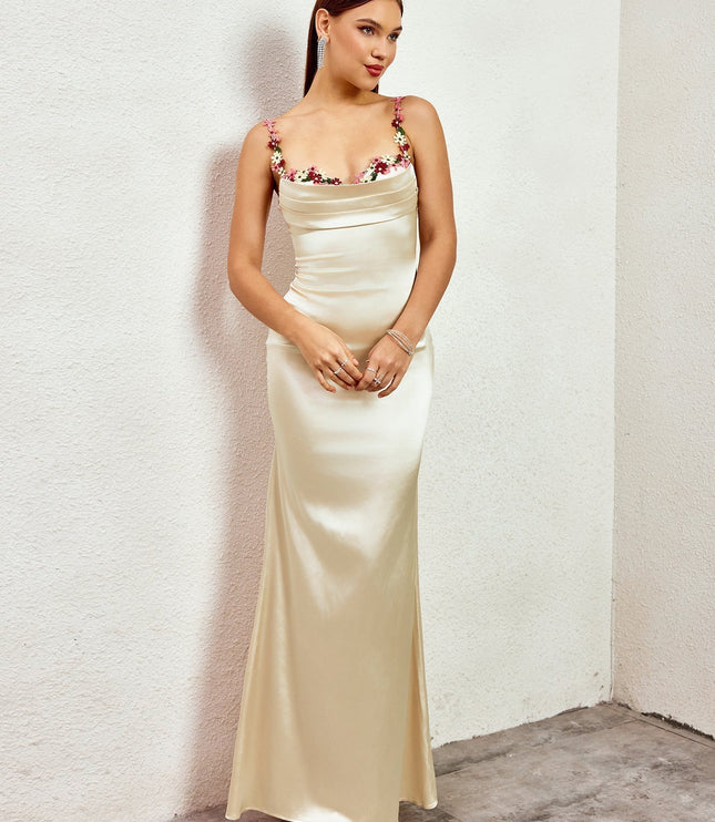 Side profile of a champagne formal maxi dress, highlighting the smooth satin fabric and delicate floral embellishments.